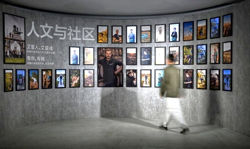 A person walking past a wall of pictures

Description automatically generated