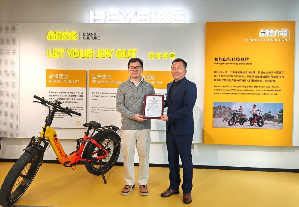 Two men standing in front of a yellow and orange sign

Description automatically generated