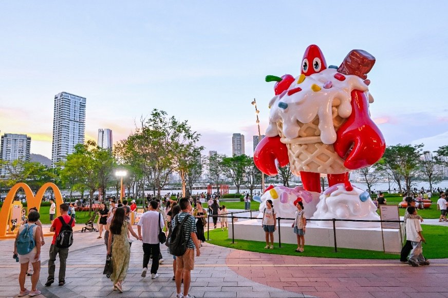 A group of people walking around a large statue of a cartoon ice cream cone

AI-generated content may be incorrect.